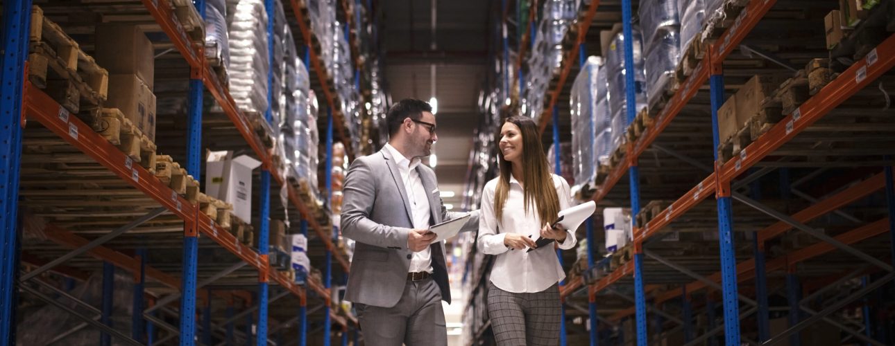 Business people walking through large distribution center and talking about increasing production and organization.